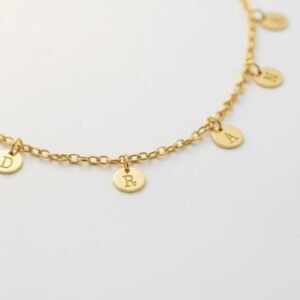 Goudkleurige Naamketting met Meerdere Rondjes Letters van Zilver Names4ever op tafel